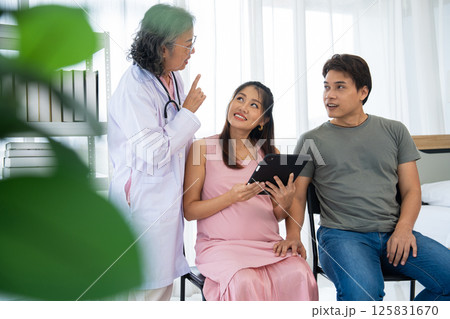 Senior female obstetrician consulting pregnant woman and her husband in medical clinic or hospital planning pregnancy. Visit to hospital, planning pregnancy, happy patients, trust and respect concept Senior female obstetrician consulting pregnant woman and her husband in medical clinic or hospital planning pregnancy. Visit to hospital, planning pregnancy, happy patients, trust and respect concept 125831670