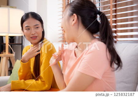 Two friends conversation and sitting on sofa in cozy living room at home, gossip with friends. 125832187