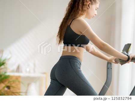 Young woman running on a treadmill indoors Young woman running on a treadmill indoors 125832794