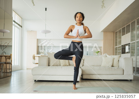 Yoga fitness workout training. Healthy African girl practicing yoga at home. Woman training Pilates doing sports exercise on yoga mat indoor. Girl have training workout for weight loss. Sport fitness 125835057