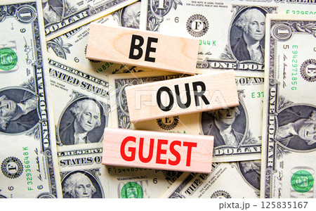 Be our guest symbol. Concept words Be our guest on beautiful wooden blocks. Dollar bills. Beautiful background from dollar bills. Business and be our guest concept. Copy space. Be our guest symbol. Concept words Be our guest on beautiful wooden blocks. Dollar bills. Beautiful background from dollar bills. Business and be our guest concept. Copy space. 125835167