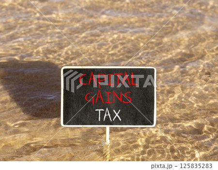 Capital gains tax symbol. Concept words Capital gains tax on beautiful blackboard. Beautiful Red sea water background. Business and capital gains tax concept. Copy space. 125835283