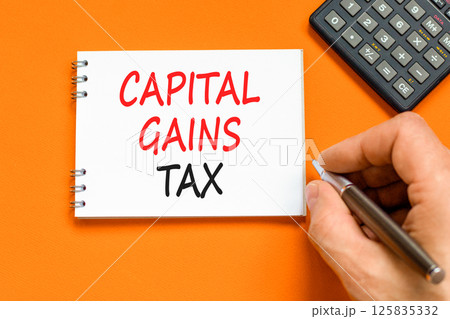 Capital gains tax symbol. Concept words Capital gains tax on beautiful white note. Beautiful orange background. Businessman hand. Business and capital gains tax concept. Copy space. Capital gains tax symbol. Concept words Capital gains tax on beautiful white note. Beautiful orange background. Businessman hand. Business and capital gains tax concept. Copy space. 125835332