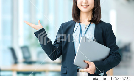 パソコンを持って手で案内をする女性・ビジネスウーマン 125835720