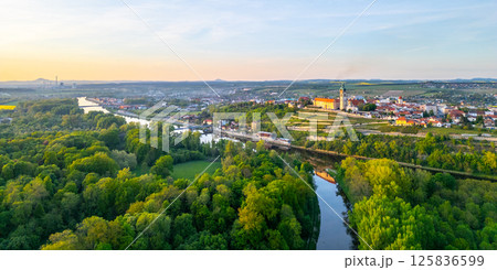 This aerial view captures Melnik City with its historic chateau situated above the Labe River. Lush greenery surrounds the river as the landscape transitions into rolling hills and farmlands. This aerial view captures Melnik City with its historic chateau situated above the Labe River. Lush greenery surrounds the river as the landscape transitions into rolling hills and farmlands. 125836599
