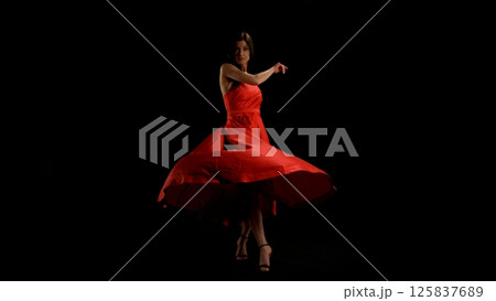 Brunette Woman in Ruby Red Dress Dancing Against a Black Background , Freeze Motion Brunette Woman in Ruby Red Dress Dancing Against a Black Background , Freeze Motion 125837689