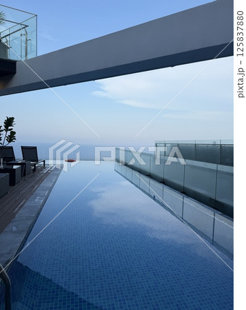vertical photo Luxury roof top swimming pool with infinity edge, early morning sunrise, colorful sky, exotic location. 125837880