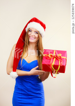 Woman in santa claus hat holds gift box. Christmas time Woman in santa claus hat holds gift box. Christmas time 125839074