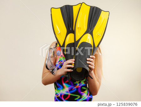 Woman covering her face with flippers having fun Woman covering her face with flippers having fun 125839076