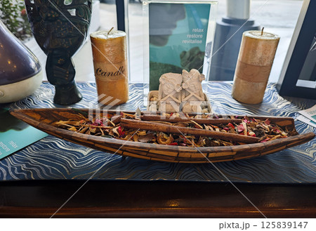 Decorative Wooden Bowl with Colorful Dried Potpourri and Cinnamon Sticks on Elegant Table with Spa Elements and Candles in Relaxing Indoor Setting Decorative Wooden Bowl with Colorful Dried Potpourri and Cinnamon Sticks on Elegant Table with Spa Elements and Candles in Relaxing Indoor Setting 125839147