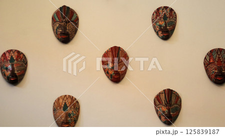 Traditional Javanese Batik Masks Displayed on a Light Beige Wall in Indonesian Cultural Exhibition 125839187