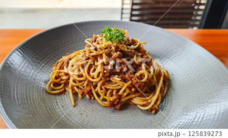Plate of Spaghetti Bolognese on Grey Plate on Wooden Table in Restaurant Setting Plate of Spaghetti Bolognese on Grey Plate on Wooden Table in Restaurant Setting 125839273