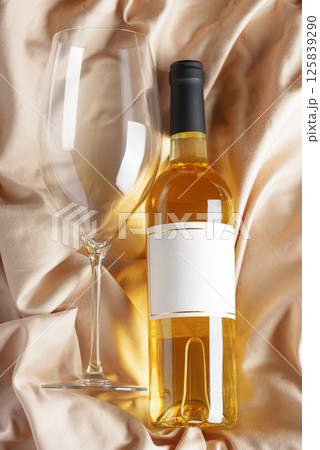 Bottle of white wine on beige satin background. Top view Bottle of white wine on beige satin background. Top view 125839290