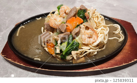 Hot Plate Noodle with Capcay Vegetables and Shrimp on Marble Table in a Restaurant Hot Plate Noodle with Capcay Vegetables and Shrimp on Marble Table in a Restaurant 125839311