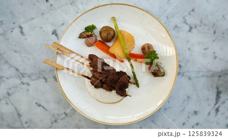 Exquisite Plated Dendeng Age Grilled Beef with Savory Sauce Vegetables and Tuber Garnish on Marble Table Exquisite Plated Dendeng Age Grilled Beef with Savory Sauce Vegetables and Tuber Garnish on Marble Table 125839324