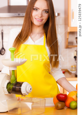 Woman in kitchen preparing fruits for juicing Woman in kitchen preparing fruits for juicing 125839479