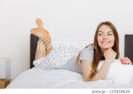Cheerful girl rolling in bed. Cheerful girl rolling in bed. 125839620