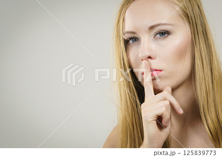 Woman asking for silence with finger on lips 125839773