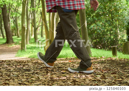 晴れた日に自然の中をカジュアルな服装で散歩する男性 125840103