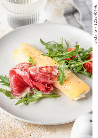 Delicious french omelette with cheese served with fresh vegetables and ham close up. Healthy diet food concept Delicious french omelette with cheese served with fresh vegetables and ham close up. Healthy diet food concept 125840446