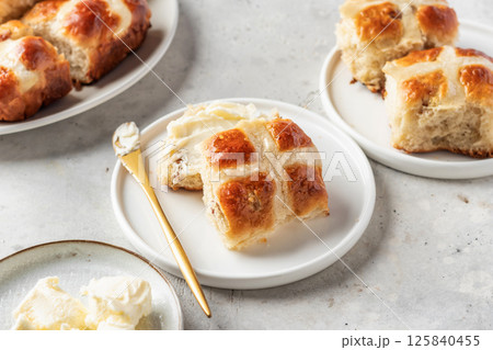 Traditional Easter hot cross buns on white plate with butter on light gray background. Delicious Easter breakfast Traditional Easter hot cross buns on white plate with butter on light gray background. Delicious Easter breakfast 125840455