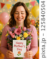 Mother Holding a Happy Mother's Day Card With a Colorful Flower Bouquet 125840504