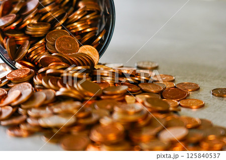 Many coins spilled from an overturned cup, concept of hoarding, success and wealth, selected focus Many coins spilled from an overturned cup, concept of hoarding, success and wealth, selected focus 125840537