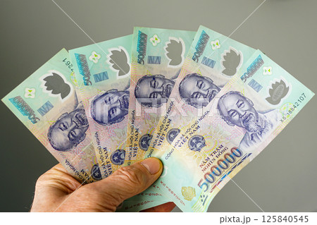 Hand holding five 500,000 dong denominations Vietnamese banknotes on a gray background Hand holding five 500,000 dong denominations Vietnamese banknotes on a gray background 125840545