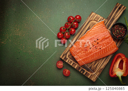 Fresh raw salmon fillet with cooking ingredients on wooden board top view on green background, space for text 125840865