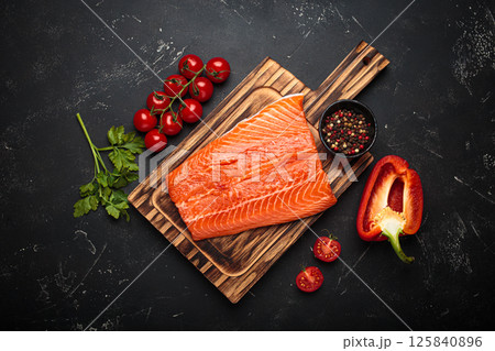 Fresh raw salmon fillet with cooking ingredients on wooden board top view on black background Fresh raw salmon fillet with cooking ingredients on wooden board top view on black background 125840896