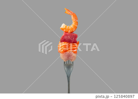 Fork holding pieces of raw salmon, beef, chicken and shrimp representing protein sources isolated on grey background Fork holding pieces of raw salmon, beef, chicken and shrimp representing protein sources isolated on grey background 125840897