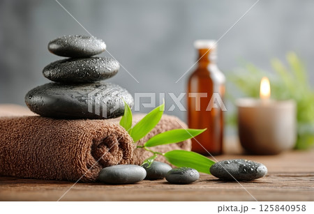 Relaxing Spa Setup With Stacked Stones and Essential Oil Bottle on Wooden Table 125840958