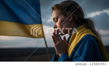 Woman praying in front of Ukrainian flag, traditional clothes, side profile 125841551