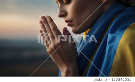 Woman praying in front of Ukrainian flag, traditional clothes, side profile 125841553