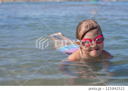 Young girl swimming in clear blue natural waters with goggles Young girl swimming in clear blue natural waters with goggles 125842521