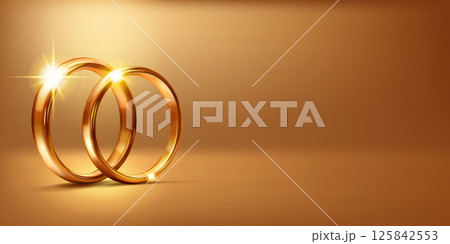 Two gold wedding rings with a glowing light. 125842553