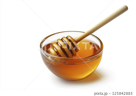 Small glass bowl of honey with wooden dipper isolated on white background with clipping path 125842883