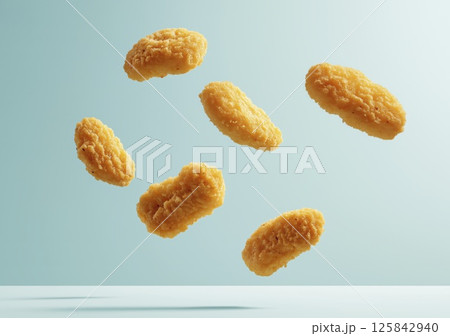 Crispy chicken nuggets falling in air on blue background with crumbs 125842940
