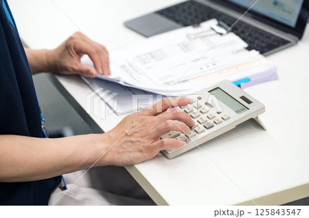 領収書の金額を電卓で計算する経理社員の手元 領収書の金額を電卓で計算する経理社員の手元 125843547