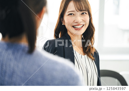 同僚と楽しく話すミドル世代のキャリアウーマン 同僚と楽しく話すミドル世代のキャリアウーマン 125843597