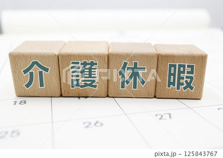 介護休暇と書かれた木のブロックがカレンダーの上に置かれている 125843767