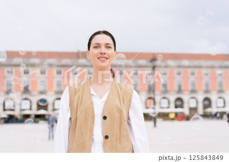 Smiling woman in brown vest standing in town Smiling woman in brown vest standing in town 125843849