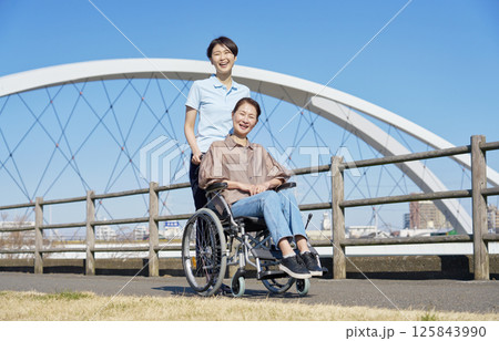 車椅子に乗った中年の女性と介護士 屋外 ポートレート カメラ目線 車椅子に乗った中年の女性と介護士 屋外 ポートレート カメラ目線 125843990