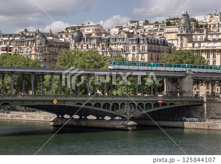 Stunning view of A metro train crossing the Pont de Bir Hakeim bridge with typical parisian buildings in the background. Stunning view of A metro train crossing the Pont de Bir Hakeim bridge with typical parisian buildings in the background. 125844107