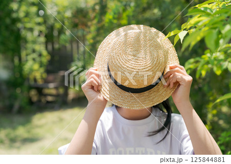 麦わら帽子で顔を隠す女の子 125844881