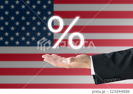 アメリカ国旗の前でパーセント記号を掲げるスーツを着た男性の手―関税イメージ 125844886