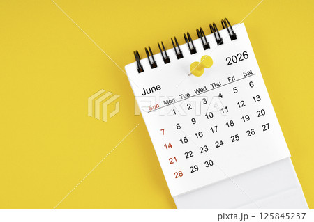 June 2026 Monthly desk calendar for 2026 year with thumbtack on yellow background. 125845237