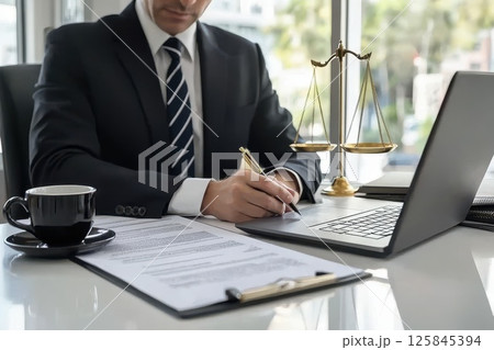 Professional Lawyer Reviewing Documents in a Well-Lit Law Office Setting Professional Lawyer Reviewing Documents in a Well-Lit Law Office Setting 125845394