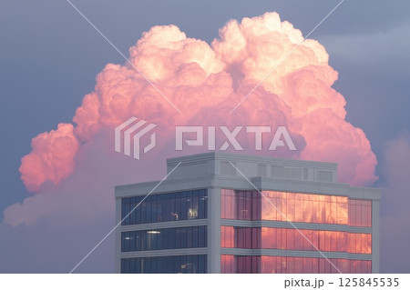 Modern Glass Building at Dusk with Vibrant Reflection of Pink Clouds in Window Facade 125845535