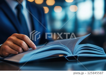 Close Up of Businessman Hands Flipping Through a Book in a Professional Setting 125845587
